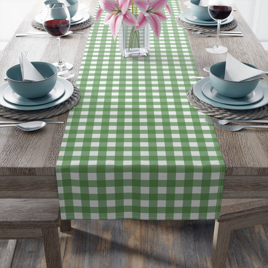Green gingham checkered table runner with green and white gingham pattern printed on front of table runner, sitting on a wood table with place settings.