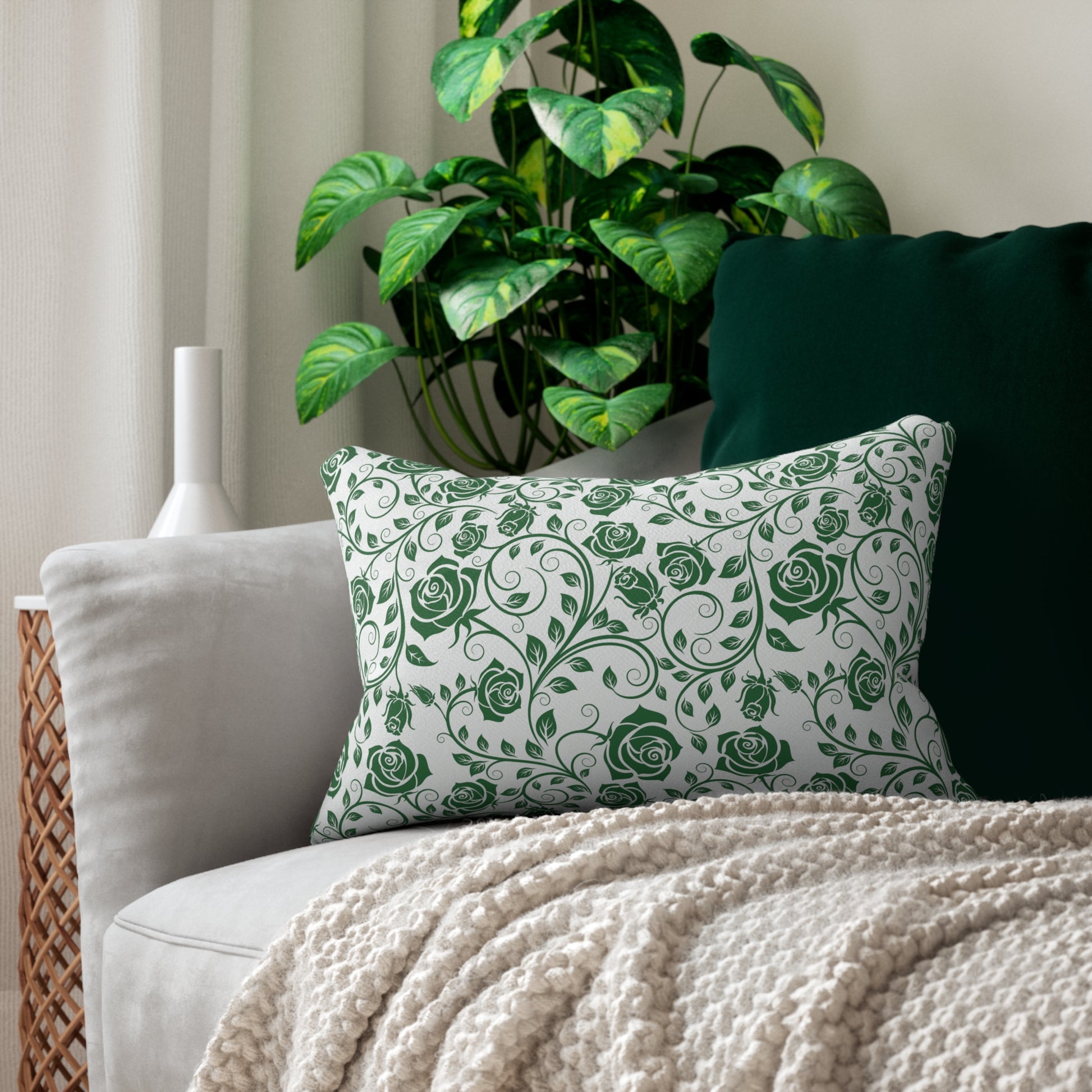 Decorative lumbar pillow with green floral pattern on a couch with a plant in the background