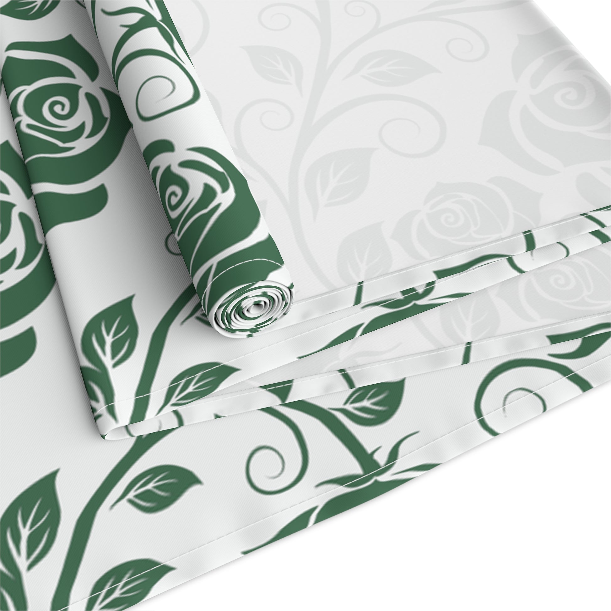 Green roses pattern table runner, rolled up and folded on white fabric