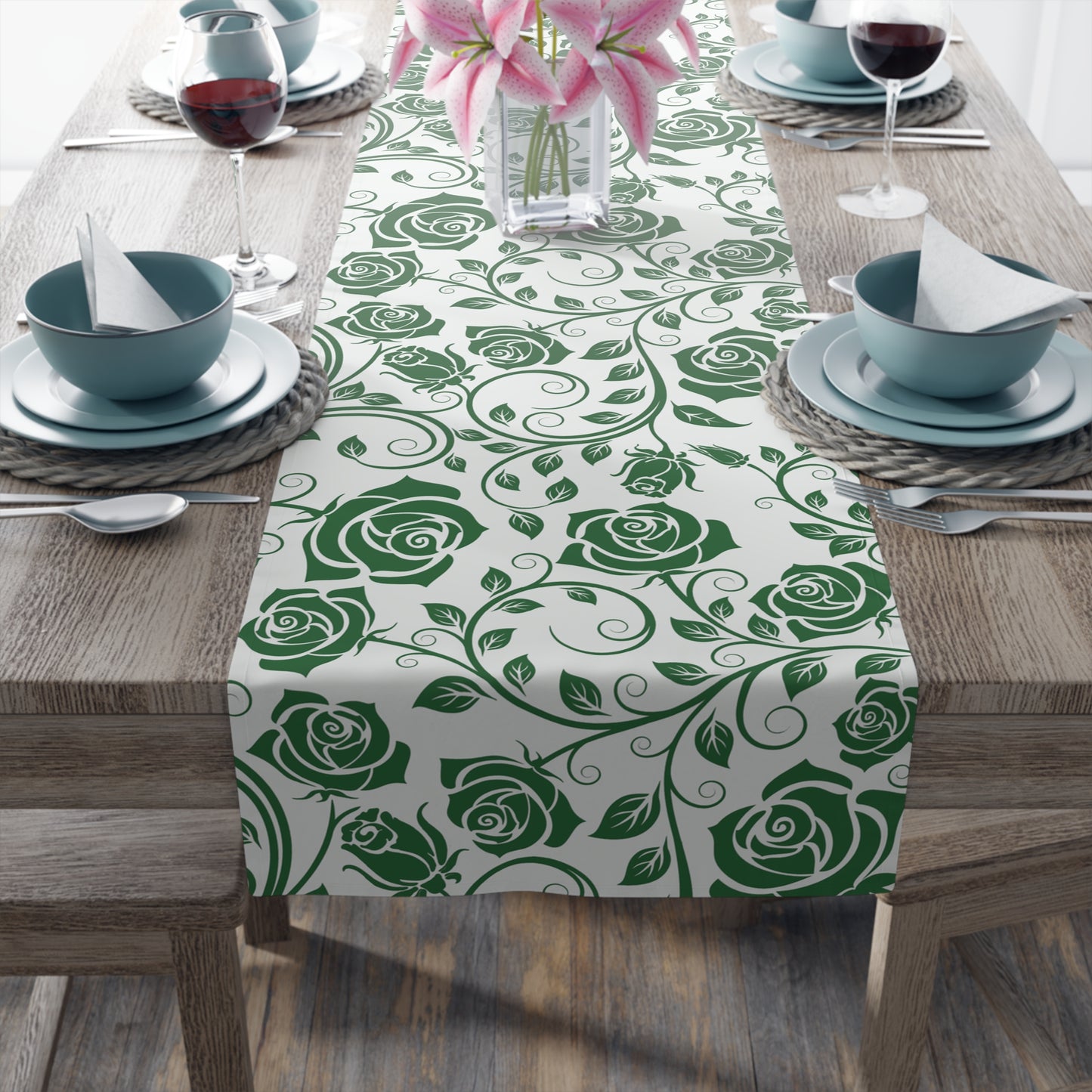 Table setting with a green rose pattern table runner on a wooden table.