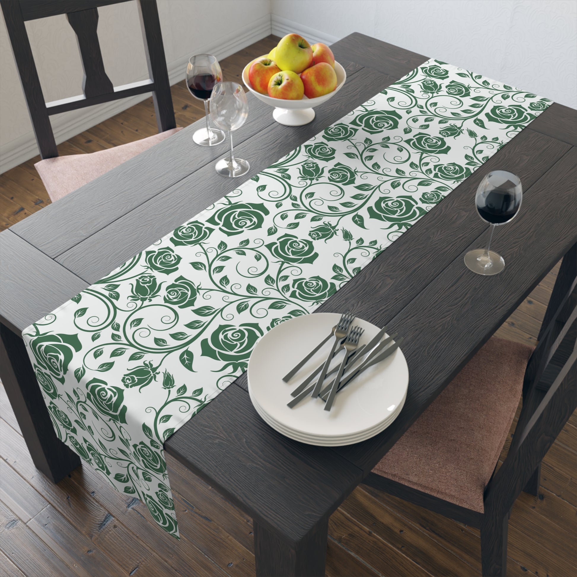 Dining table with a green floral table runner, plates, and cutlery.