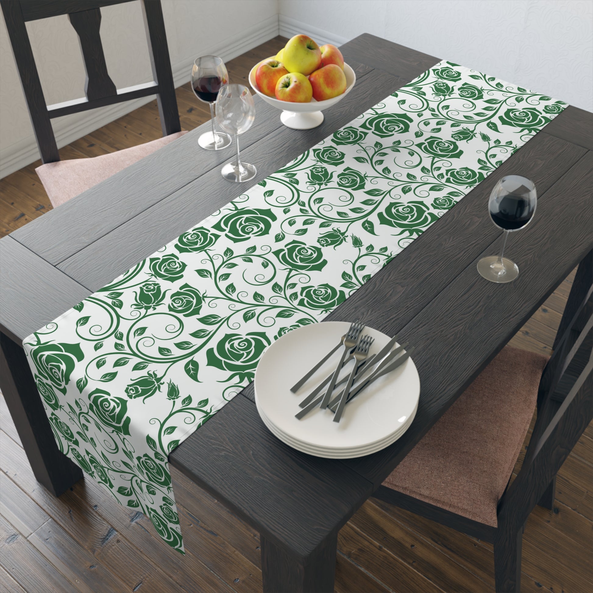 Dining table with a green floral table runner, plates, cutlery, and fruit.