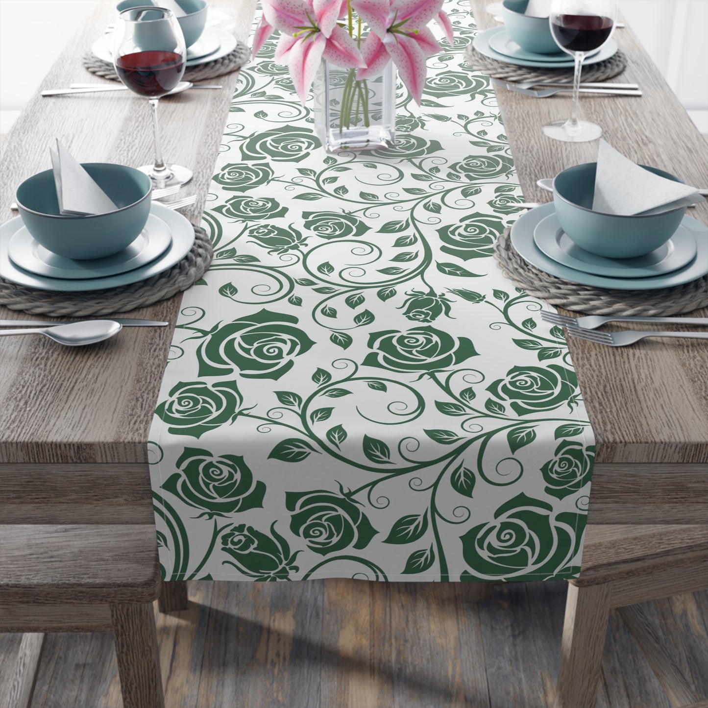 Table setting with a green rose patterned table runner on a wooden table.