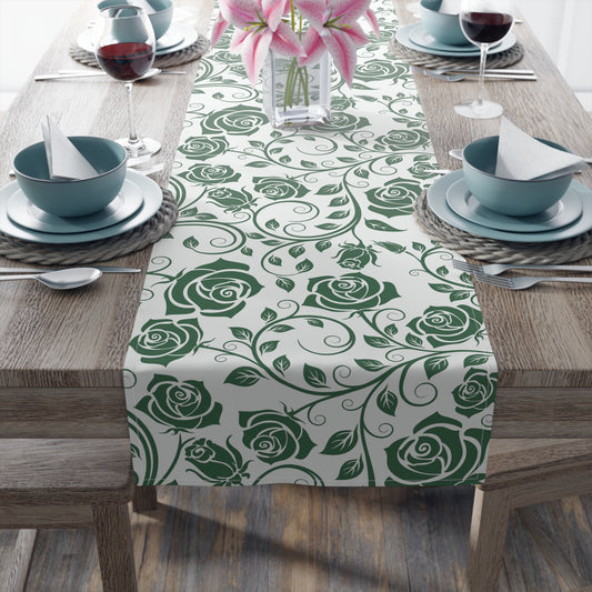 Table setting with a green rose patterned table runner on a wooden table.