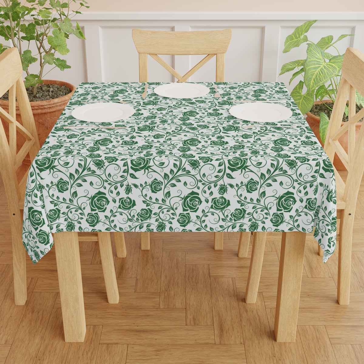 Table with a green floral patterned tablecloth on a wooden table and chairs.
