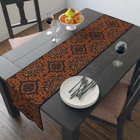 Groovy Black & Orange table runner with intricate black and orange pattern printed on the cotton twill table runner that is set on a dark colored dining table with plates, cutlery, and fruit on a wooden floor.