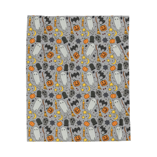 Halloween-themed patterned blanket with ghosts, pumpkins, and stars on a gray background on front of blanket, on a white background.