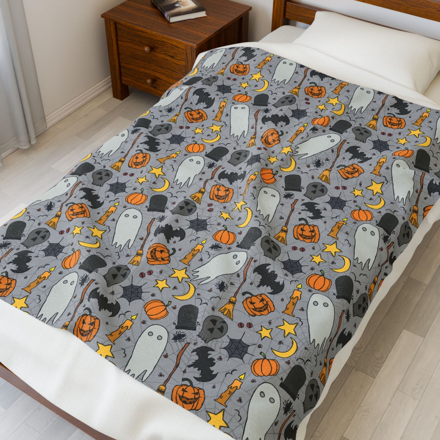 Halloween-themed bedding with ghosts, pumpkins, and ghosts on front of blanket, on a bed in a bedroom.