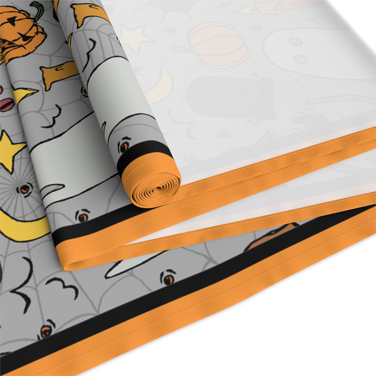 Halloween-themed table runner with ghosts, pumpkins, and bats with a gray background on front of table runner, rolled up and folded on a white background.