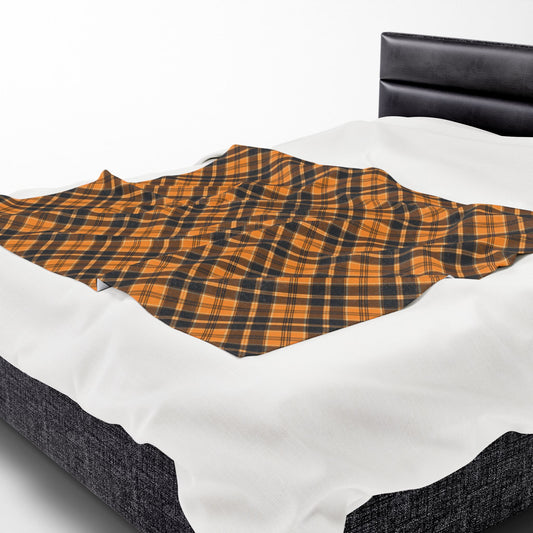 Halloween Plaid throw blanket with orange and black plaid pattern on front of blanket, on top of bed linens  on a bed