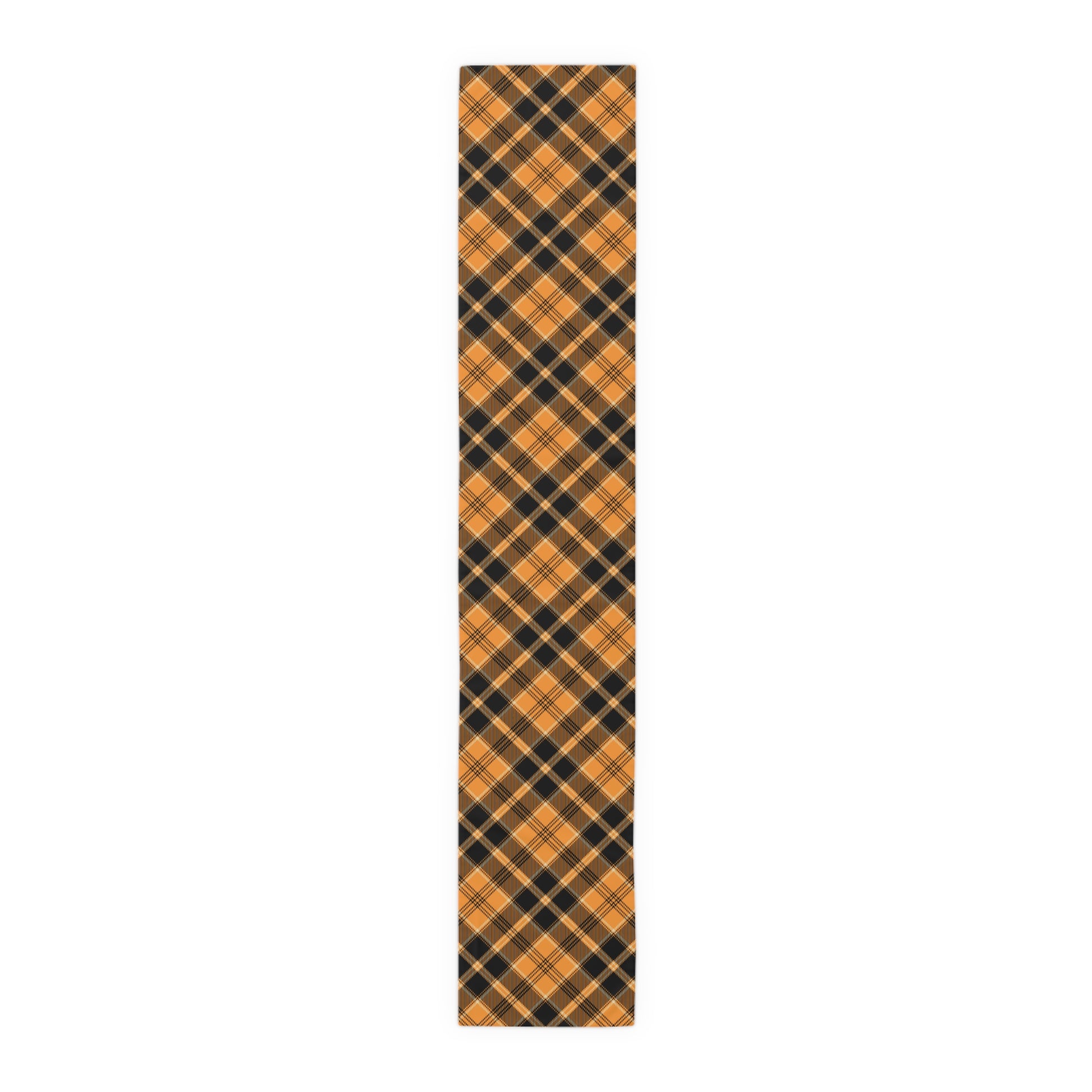 Pumpkin plaid table runner has a patterned black and orange plaid pattern on front of table runner, on a white background