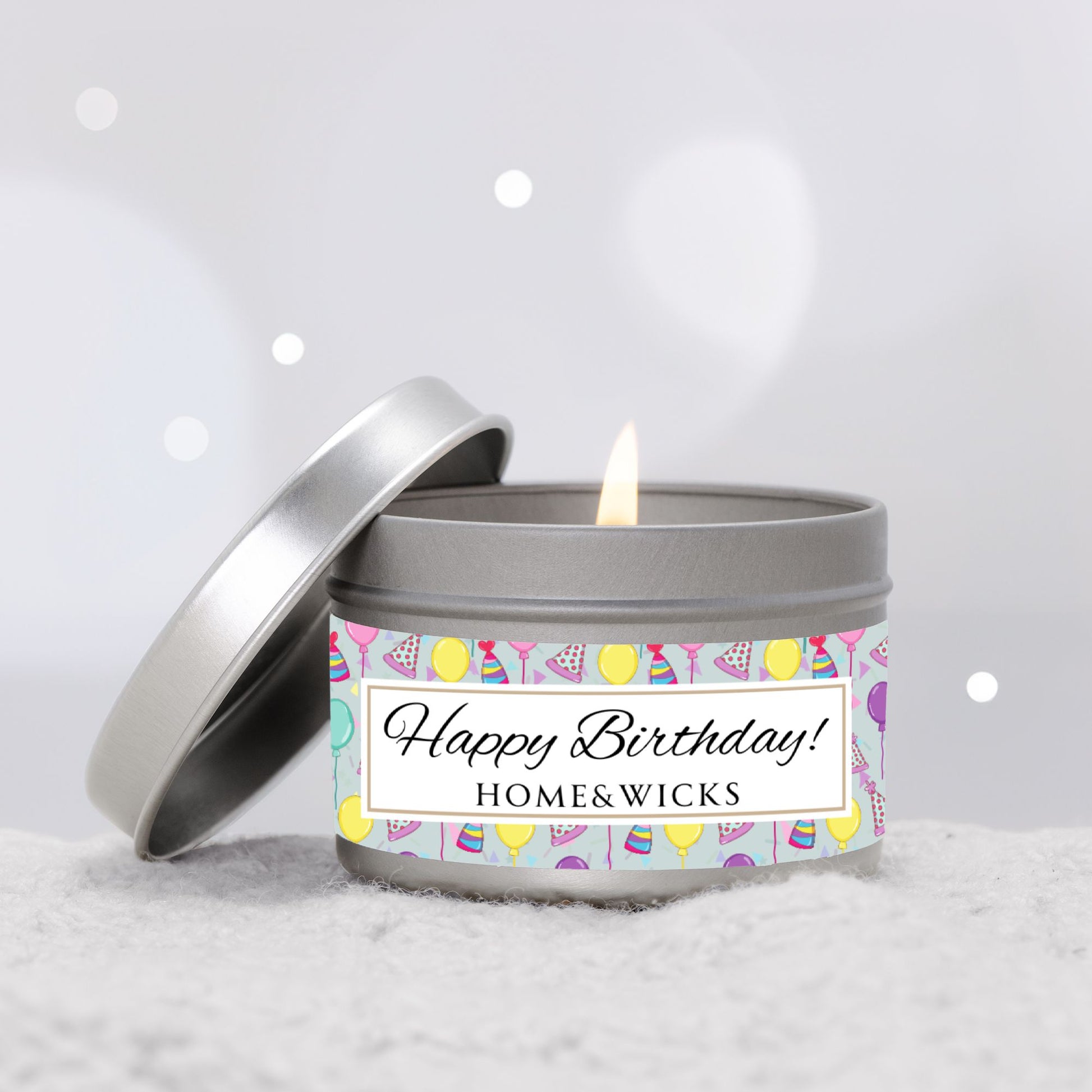Happy Birthday silver candle 4 oz. tin with 'Happy Birthday' label with colorful design of birthday hats, balloons and confetti on a light gray background