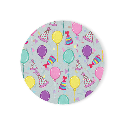 Round Happy Birthday! hardboard coaster with colorful balloons, birthday party hats and confetti pattern with  a light blue gray background on a white background