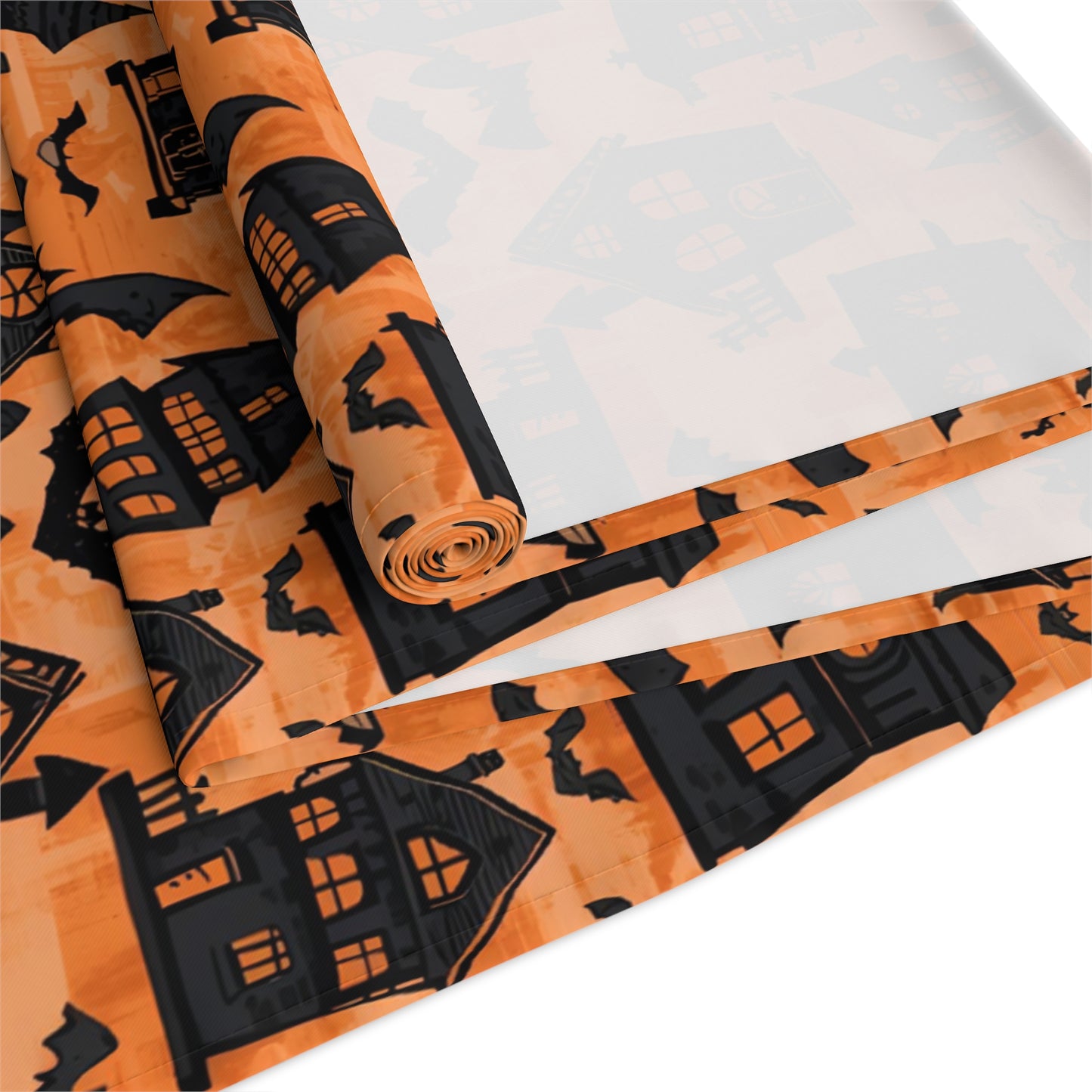 Black Haunted Houses table runner with black haunted houses and bats on an orange background design printed on the table runner is rolled up on a white background