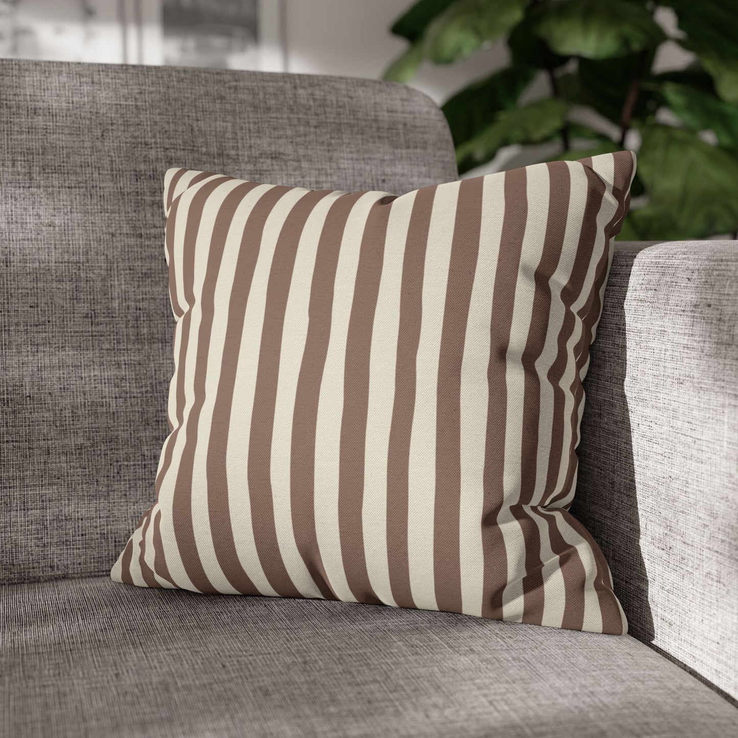 Mocha brown and beige striped pillow on a gray sofa with a blurred indoor background