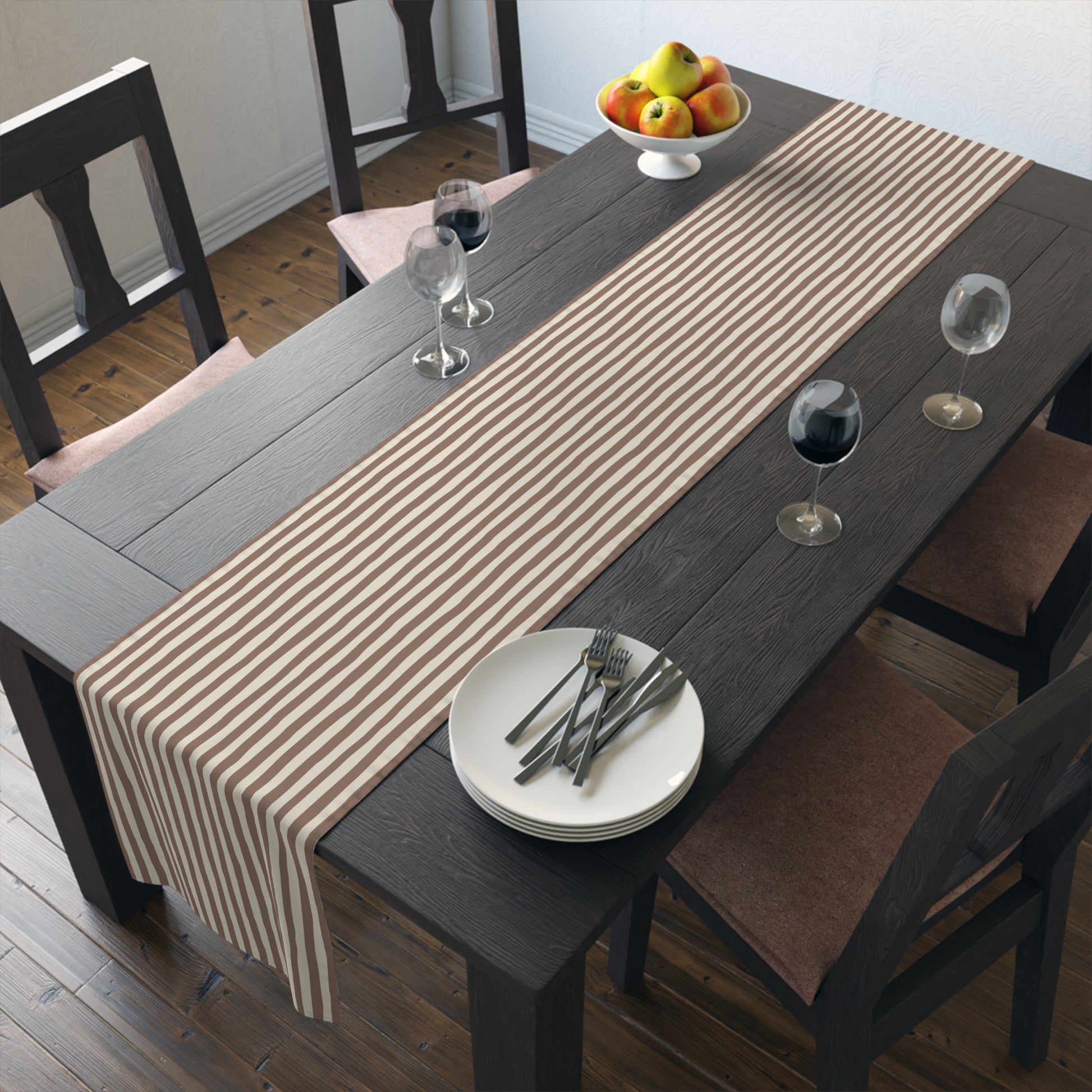 Dining table with mocha brown and beige striped runner, plates, and glasses in a room setting.