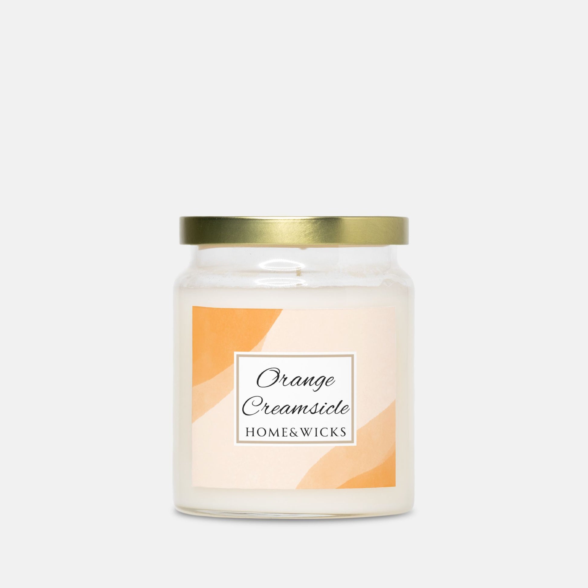 Candle with a gold lid and 'Orange Creamsicle' label on a white background