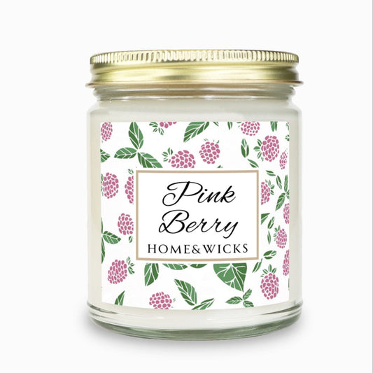 Pink Berry clear candle jar with gold lid with a decorative label featuring pink berries and green leaves on a white background by Home & Wicks