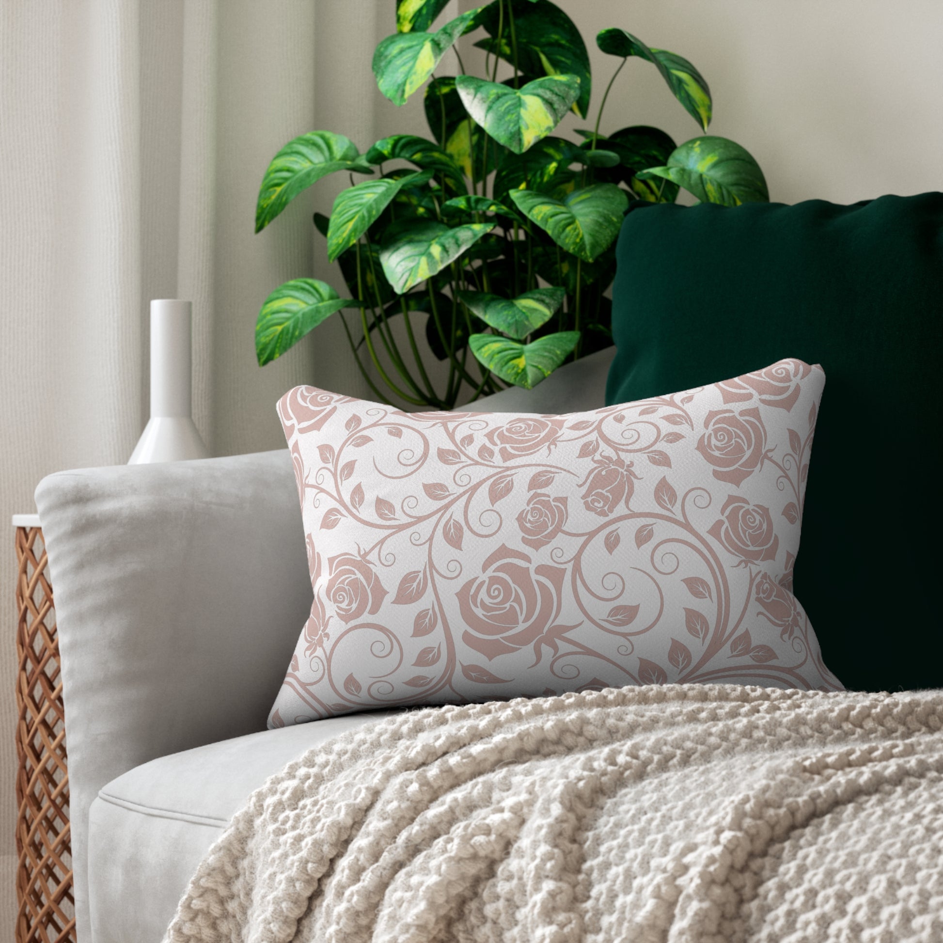 Decorative pillow with pink floral pattern on a couch with a plant in the background