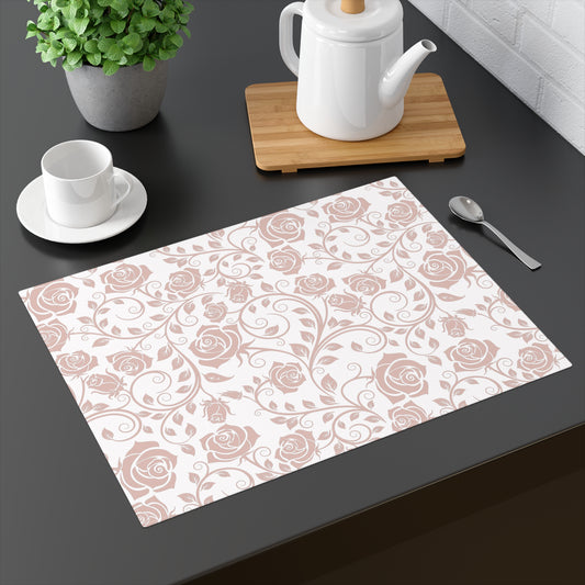 Floral pink rose patterned placemat on a dark surface with a teapot, cup, and spoon.