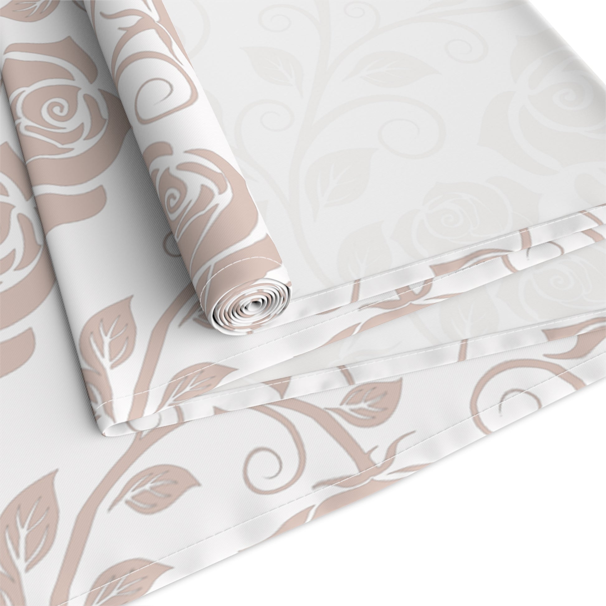 Table runner with pink floral pattern rolled up and folded on a white background