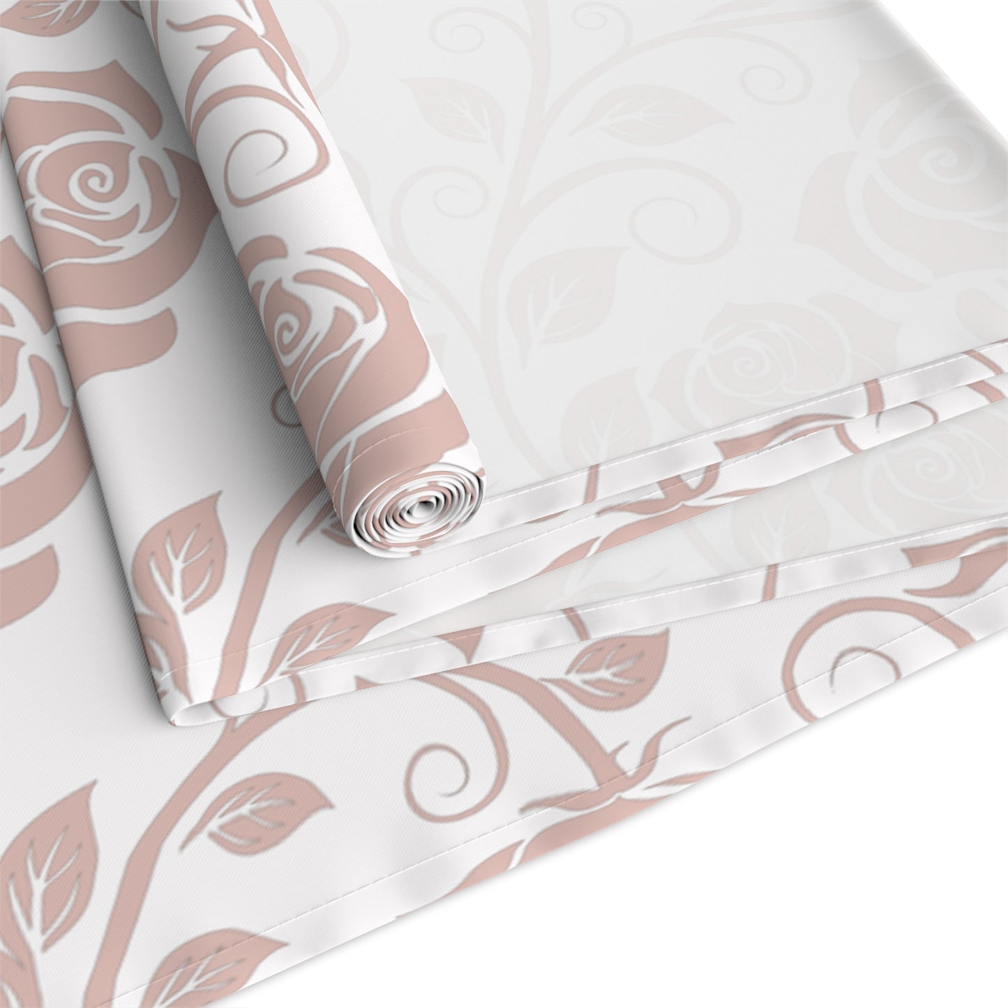 Table runner with pink floral pattern rolled up and folded on a white background
