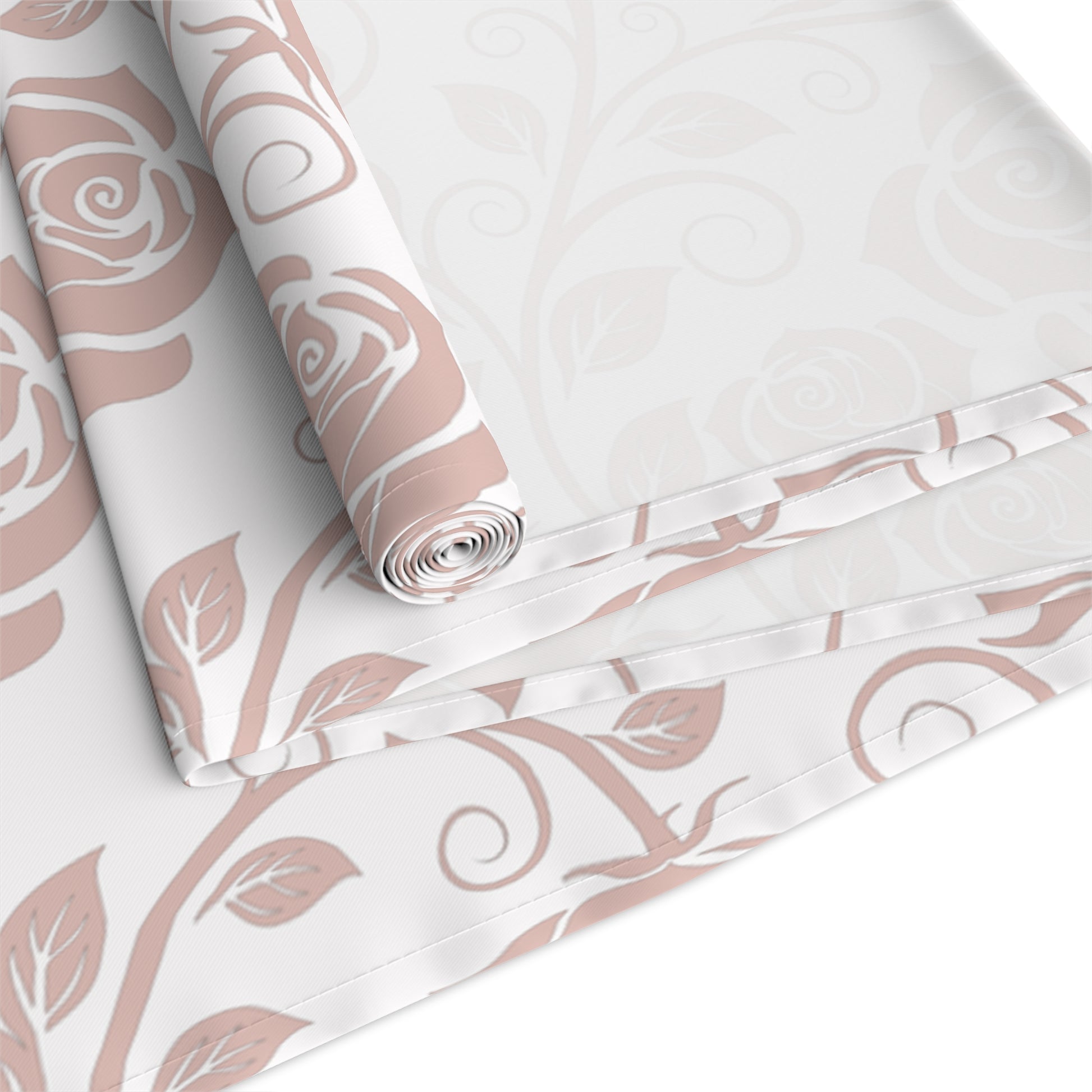 Table runner with pink floral pattern rolled up and folded on a white background