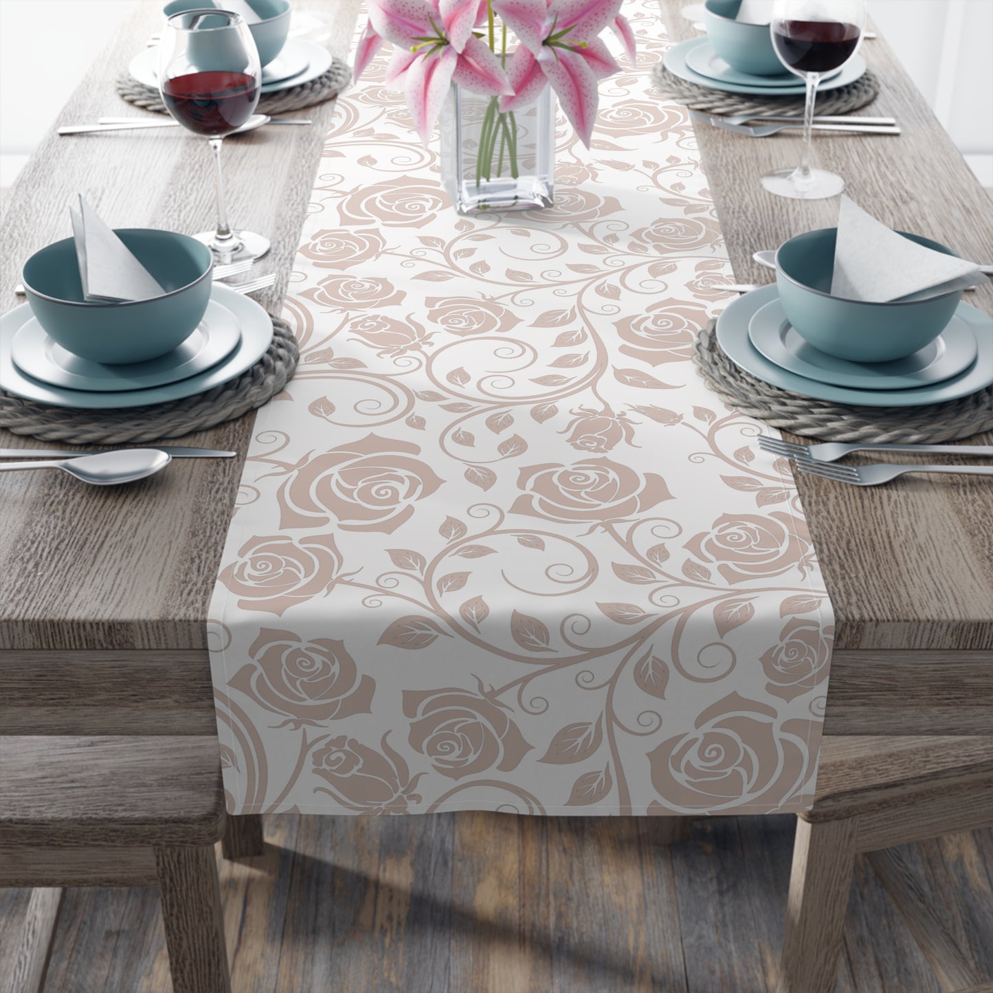 Dining table set with a pink floral patterned table runner, blue bowls, and pink flowers.