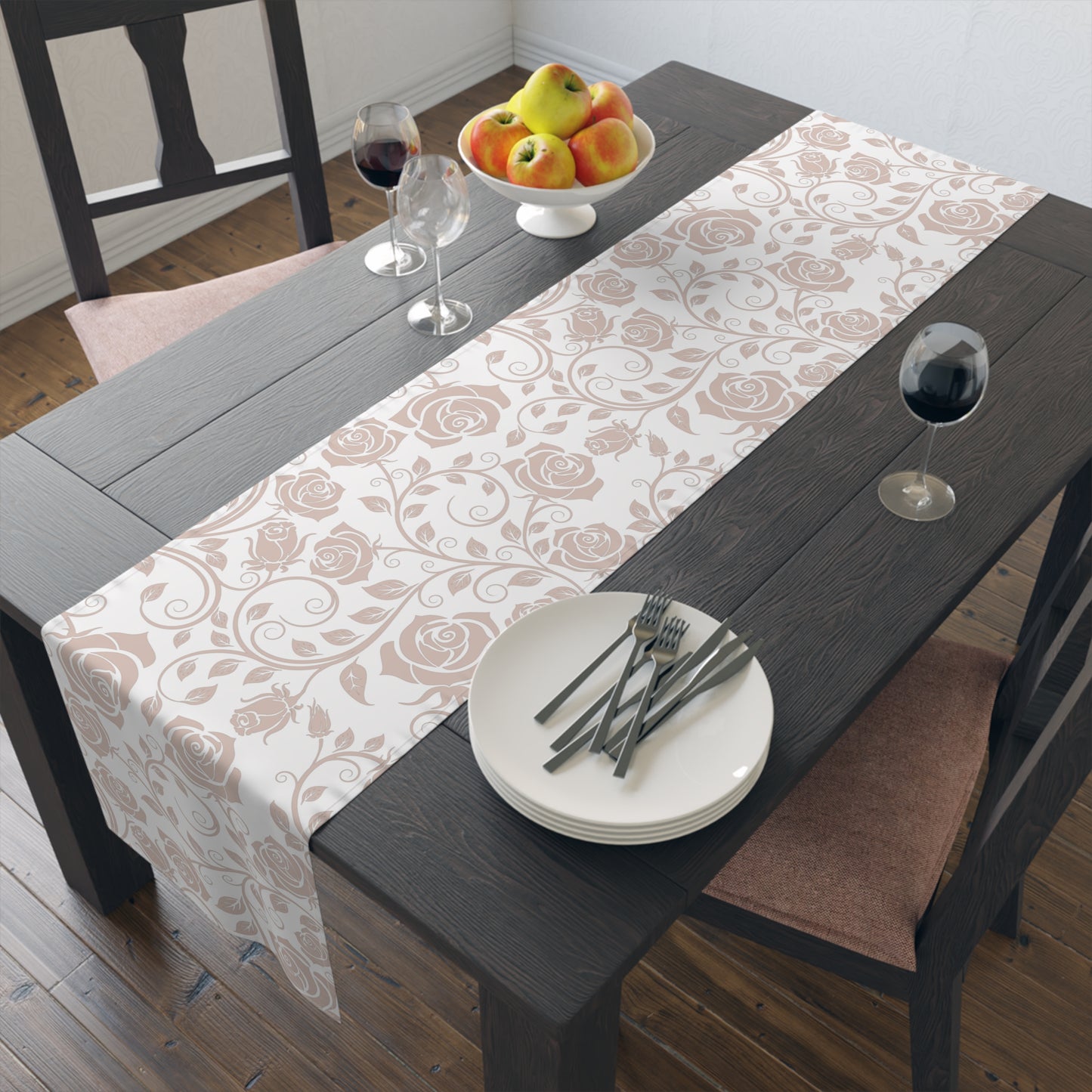 Dining table with a pink floral table runner, plates, cutlery, and fruit bowl.