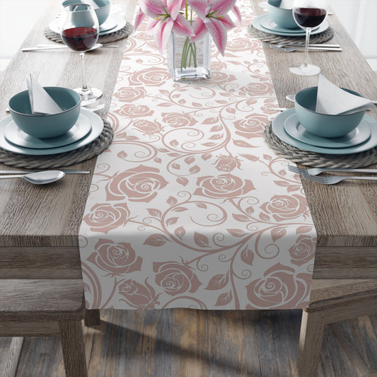 Table setting with a pink floral table runner on a wooden table.
