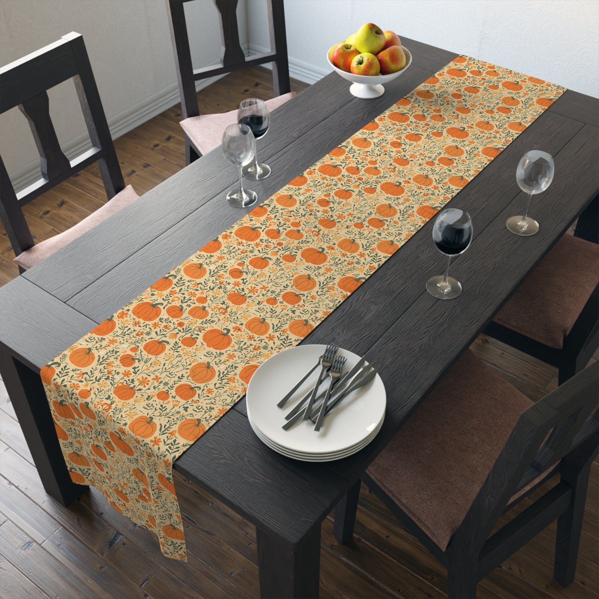 Our Pumpkin Garden table runner has an orange pumpkin and flowers table runner design and sits on a dining table with plates, and glasses in a room.