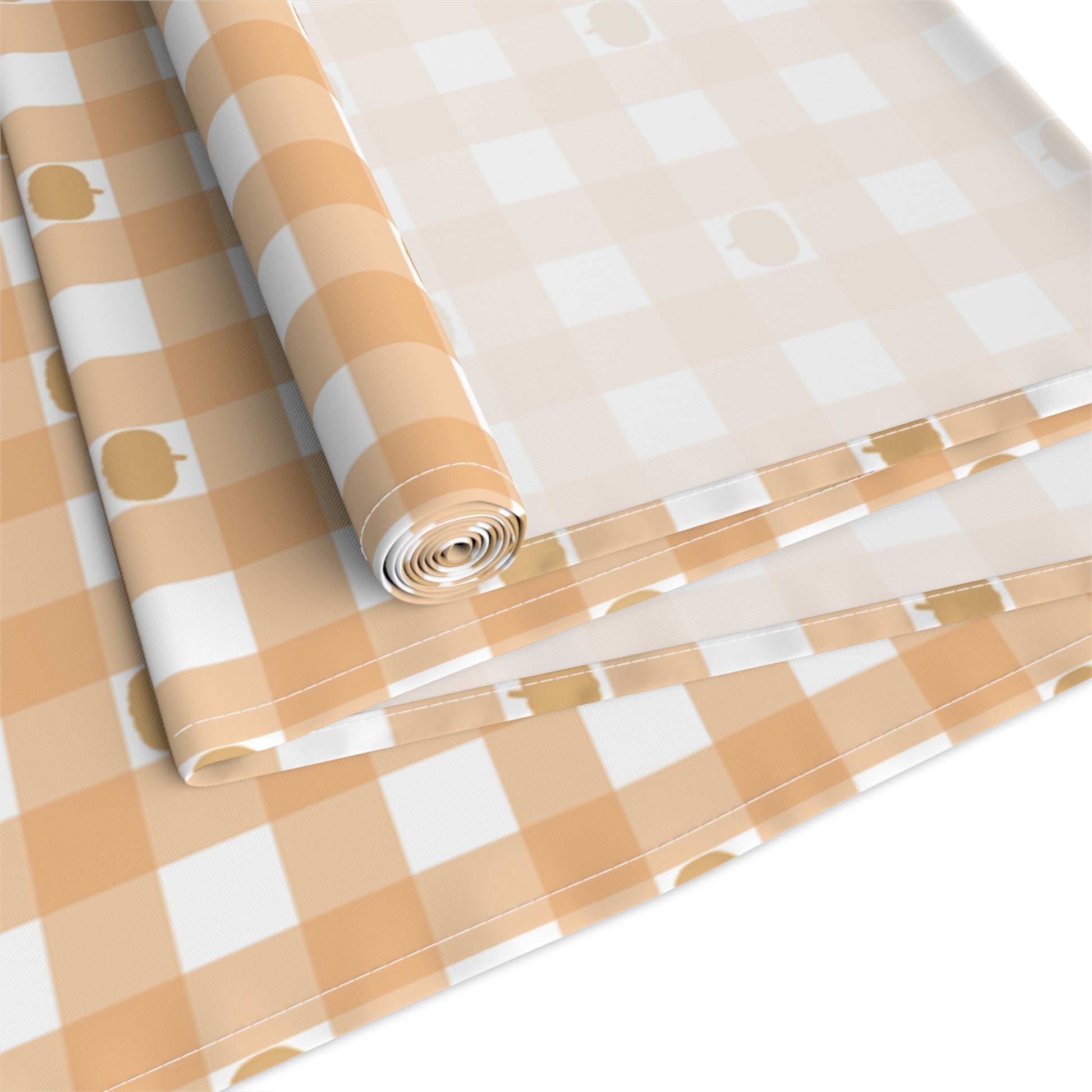Our cotton twill Pumpkin Gingham table runner has an orange and white checkered pattern with small pumpkins on the table runner fabric  and is rolled up on a white background