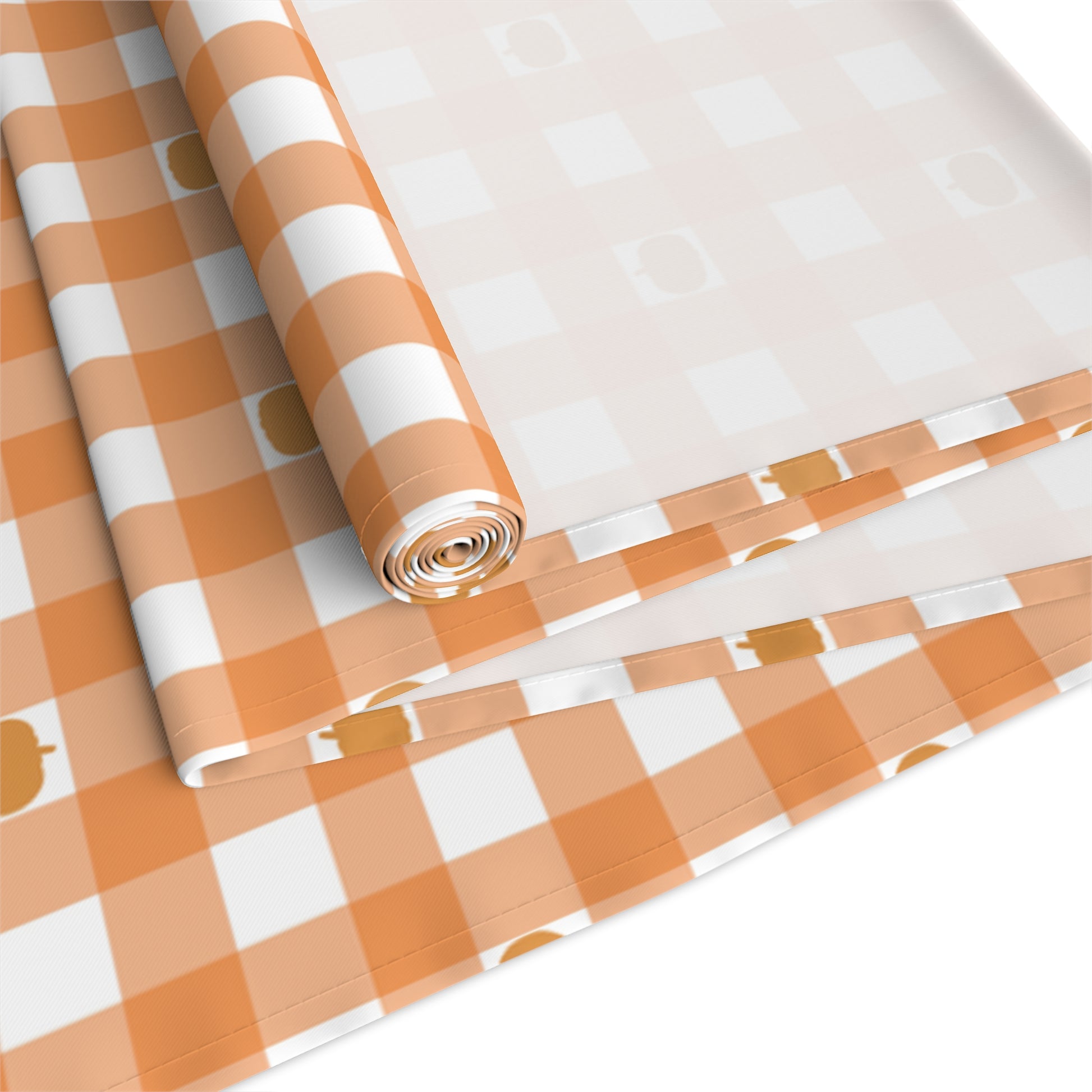 Our polyester Pumpkin Gingham table runner has an orange and white checkered pattern with small pumpkins on the table runner fabric  that is rolled up on a white background