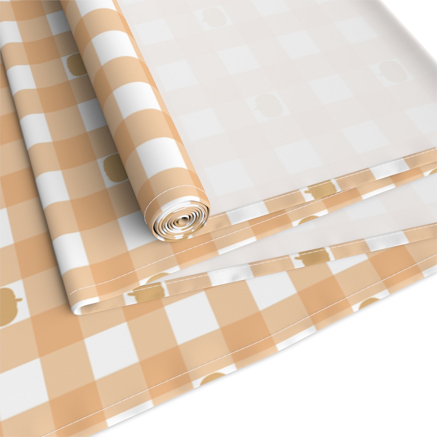 Our Pumpkin Gingham table runner has an orange and white checkered pattern with small pumpkins on the table runner cotton twill fabric and is rolled up on a white background