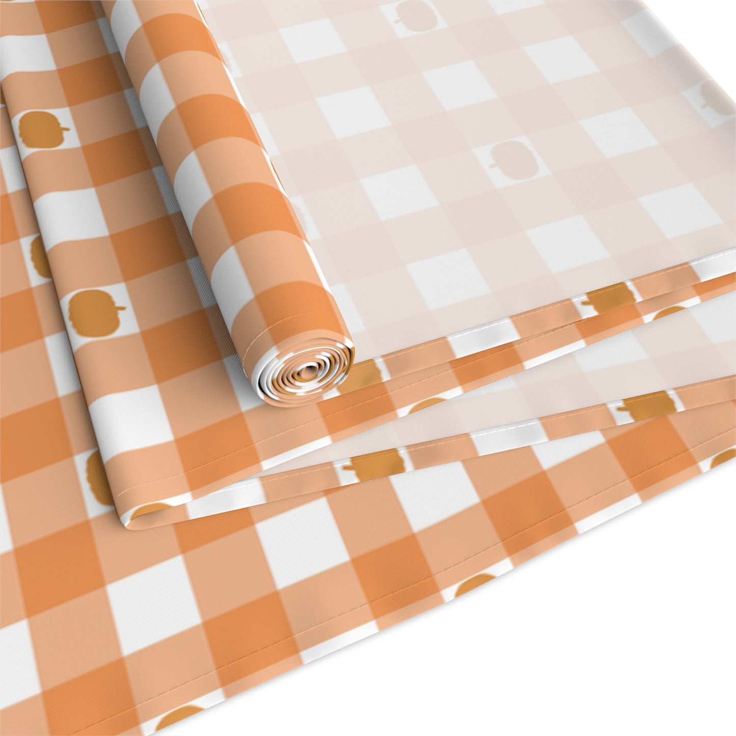 Our polyester Pumpkin Gingham table runner has an orange and white checkered pattern with small pumpkins on the table runner fabric and is rolled up on a white background