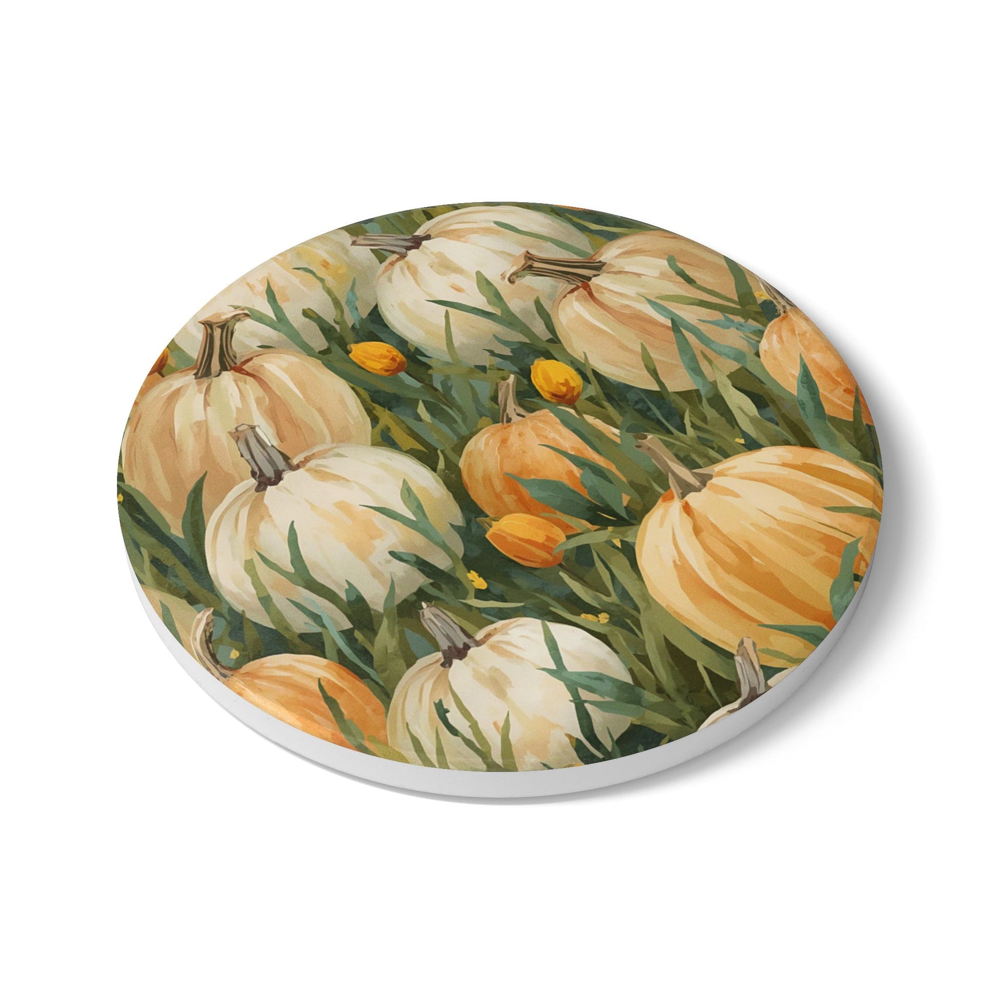 Round ceramic coaster with Pumpkin Patch design has white and orange pumpkins in grass with orange tulips printed on top of the tile coaster  on a white background