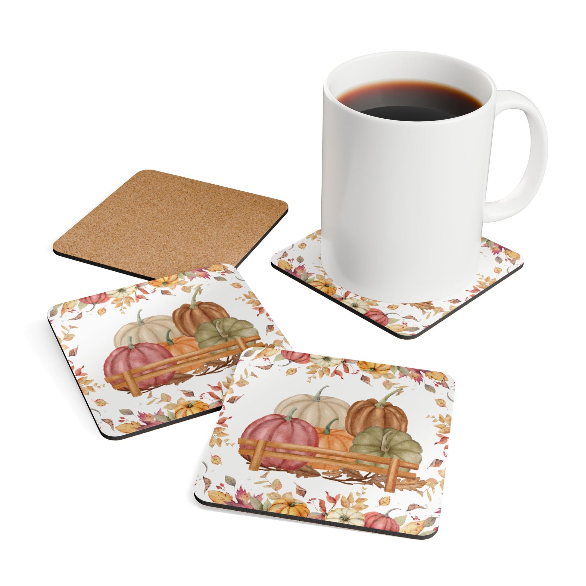 Set of four decorative coasters with pumpkins and leaves design, one coaster with a cork back, and a white mug with coffee.