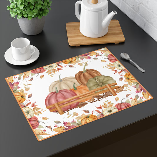 Pumpkins placemat with pumpkins and autumn leaves on the placemat's cotton twill fabric, with a white background on a dark table with teapot and teacup.