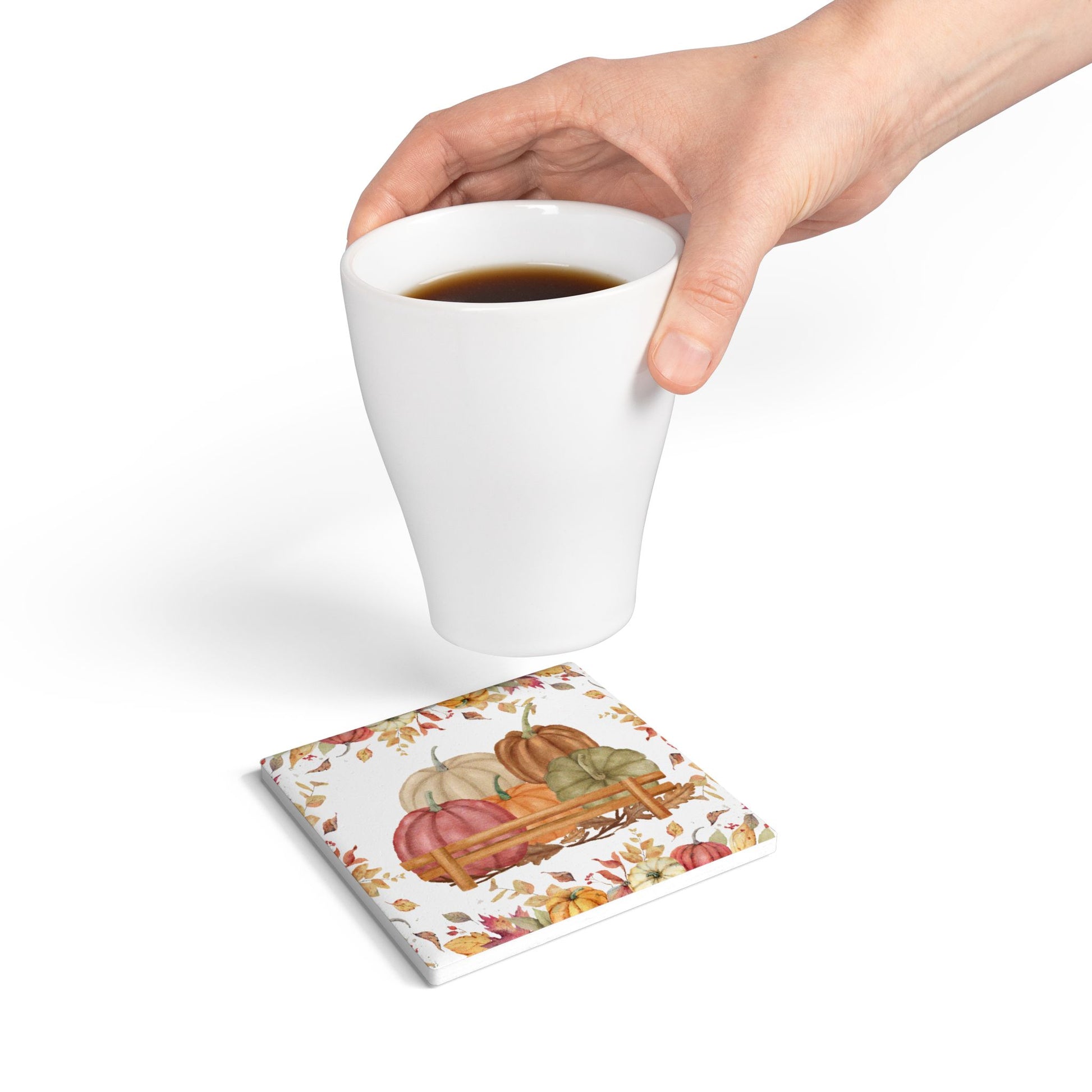 Tile coaster with autumn pumpkin design with hand holding a white mug with coffee