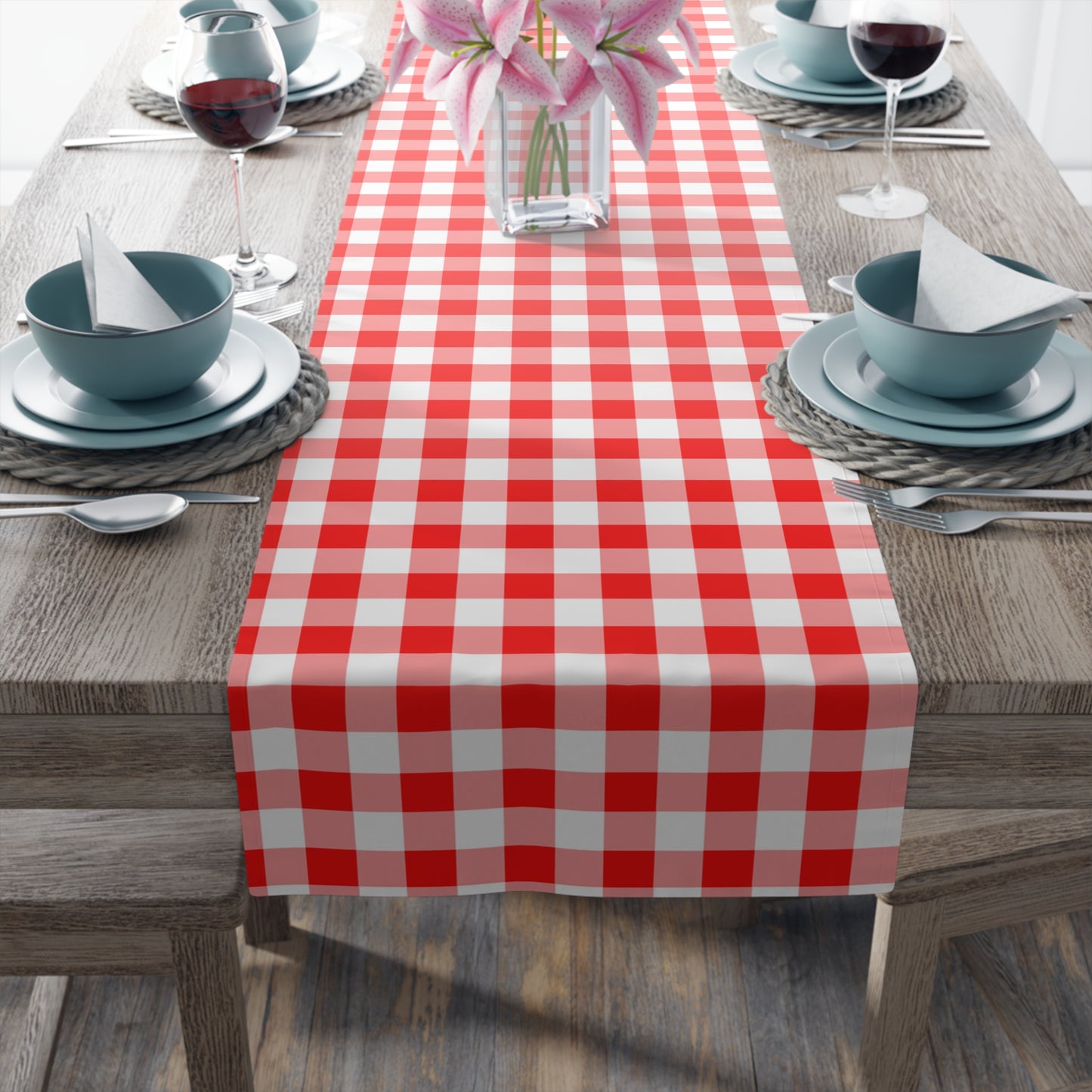 Red and white gingham checkered table runner on a wooden table with place settings.