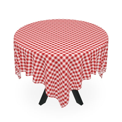 Dining table with a red and white gingham checkered tablecloth, surrounded by wooden chairs on a wooden floor.