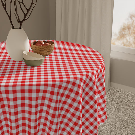 Round table with red and white gingham checkered tablecloth, vase, and bowl in a room.