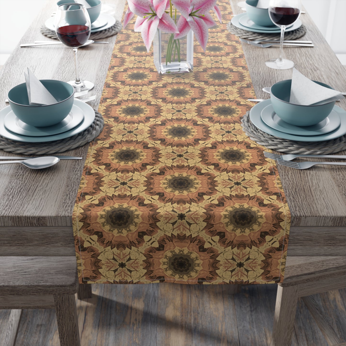 Dining table set with an orange, gray and yellow patterned cotton table runner, bowls, and glasses on a wooden table.