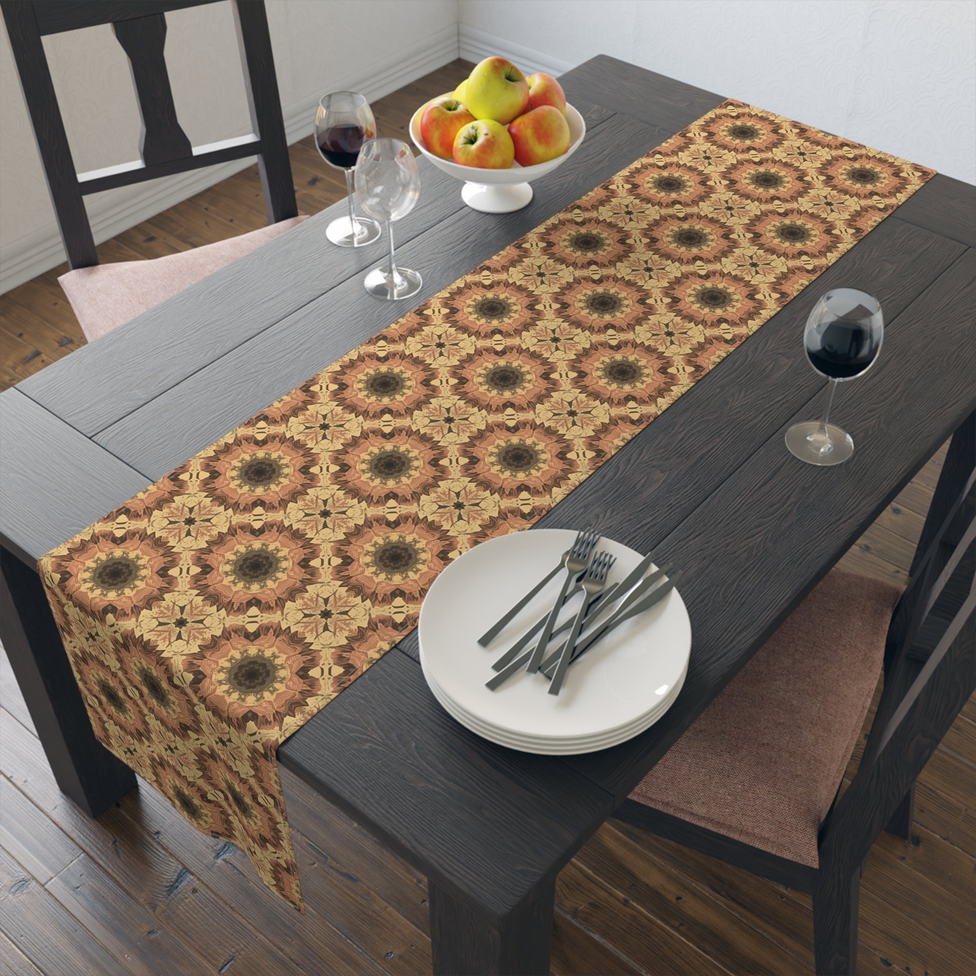 Dining table with an orange, yellow and gray tye-dye patterned table runner, plates, forks, and a fruit bowl.