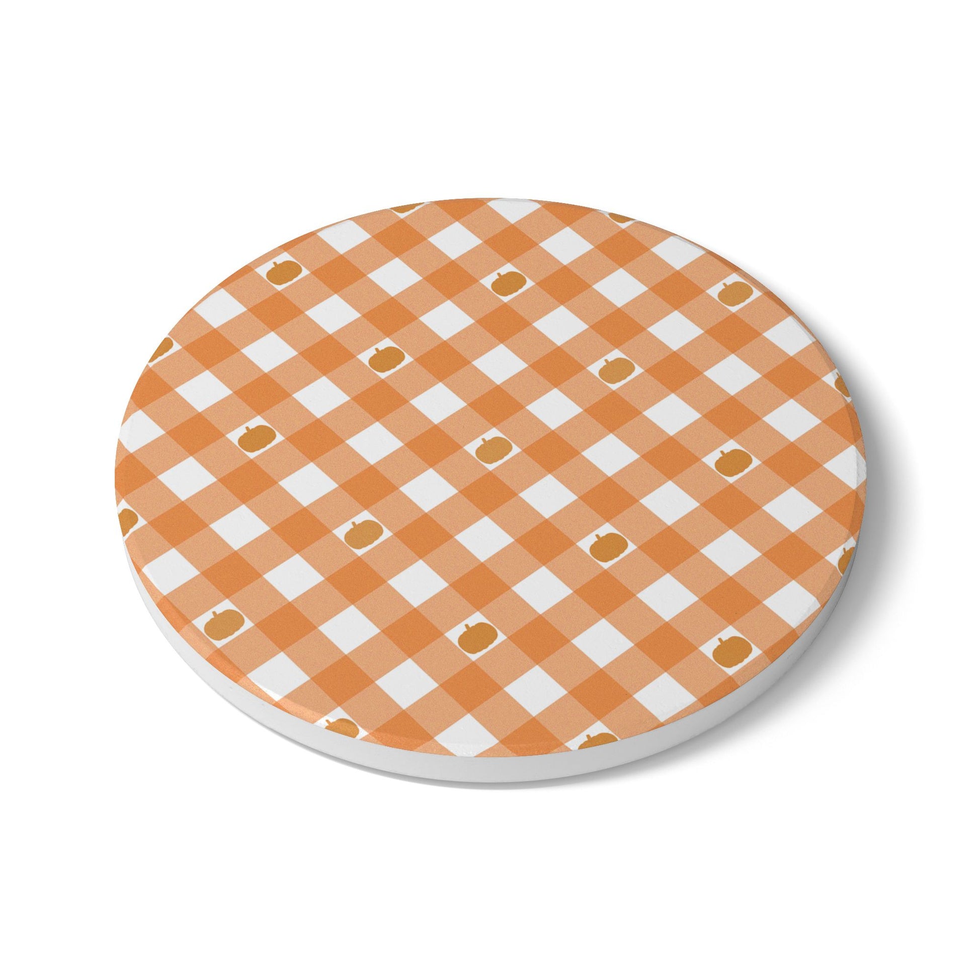 Round ceramic tile coaster with orange and white gingham checkered pumpkin pattern on a white background