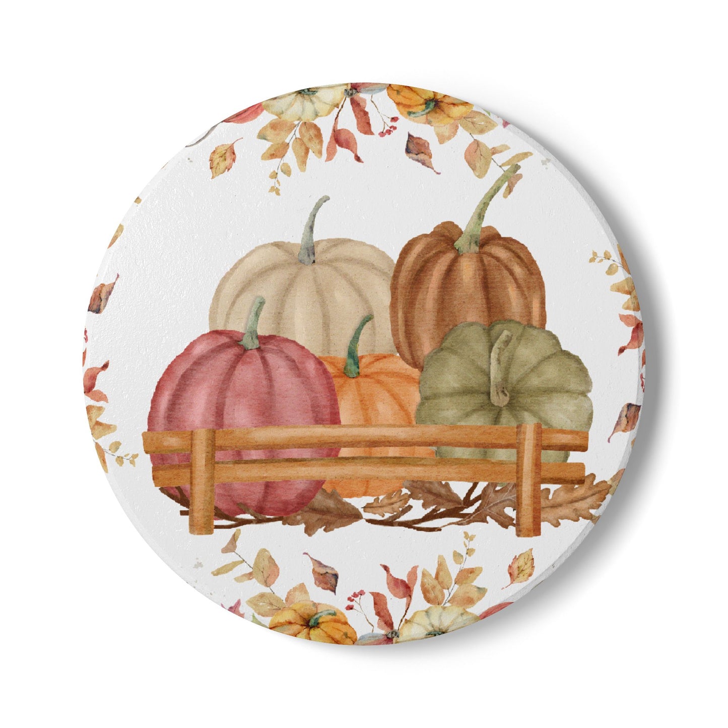 Round tile coaster with pumpkins and autumn leaves on a white background