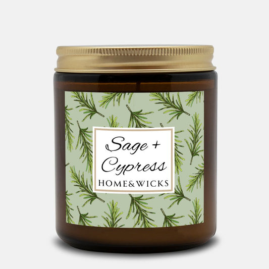 Sage & Cypress candle in an amber jar with gold lid with 'Sage + Cypress' label on a light green background with cypress needle leaves