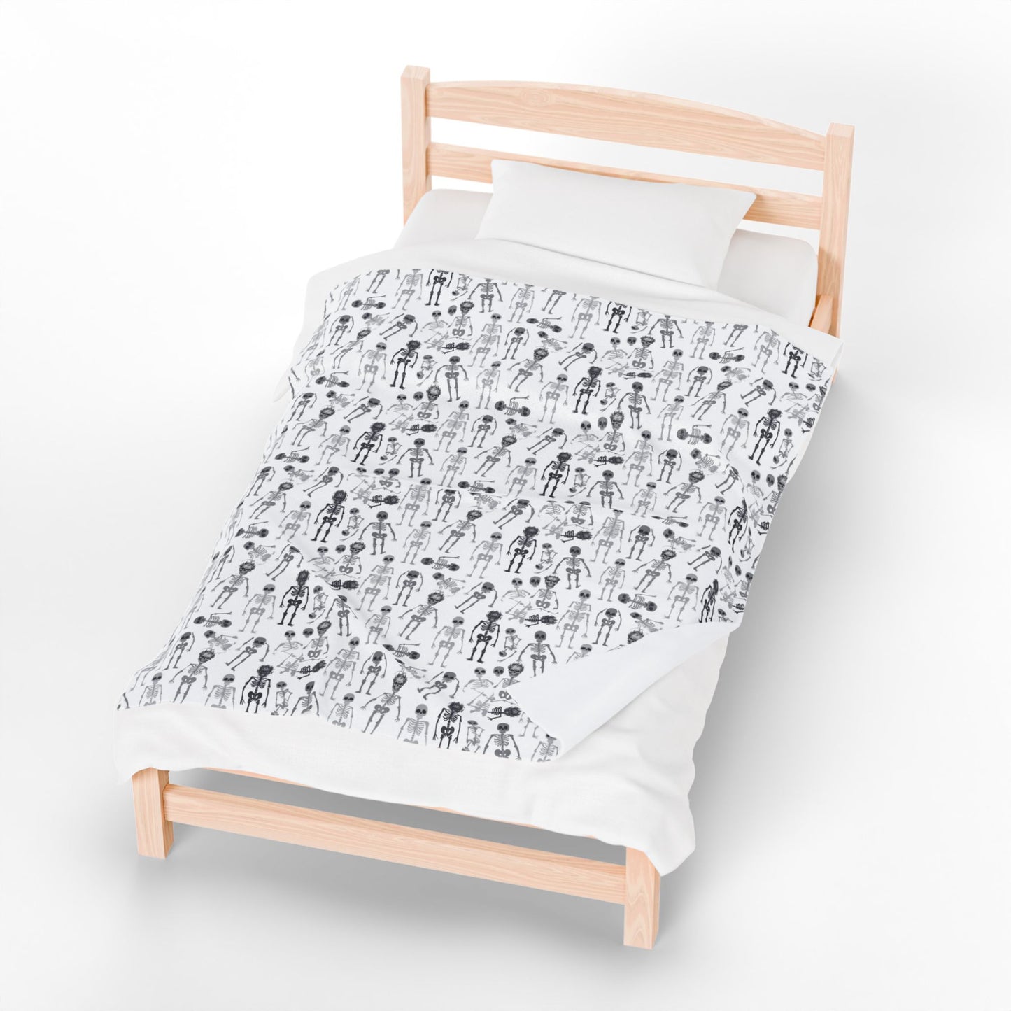 Halloween-themed Skeletons patterned blanket with black and white skeletons on a white background on front of blanket, on a bed on a white background