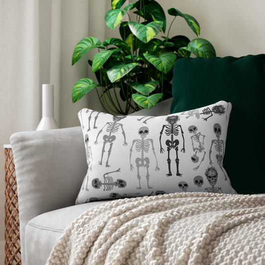 Skeletons decorative lumbar pillow has black and white skeleton design on both sides of pillow, on a couch with a plant in the background