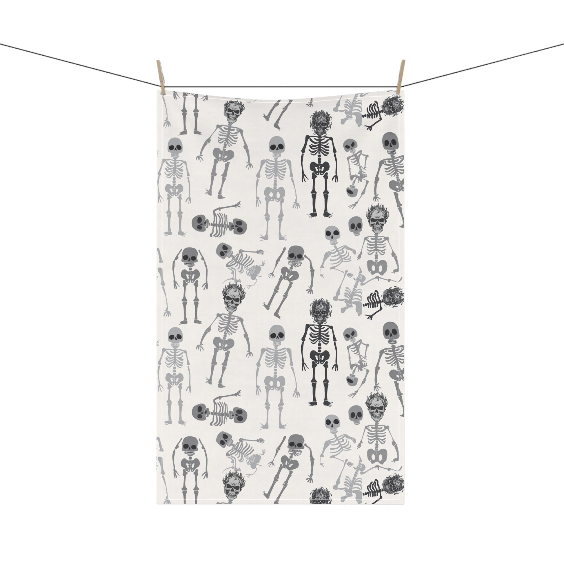 Skeletons tea kitchen towel with black and white skeleton pattern on front of towel, hanging on a line